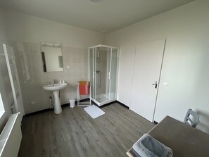 Ein modernes Badezimmer mit Waschbecken, Spiegel und einer Duschkabine.