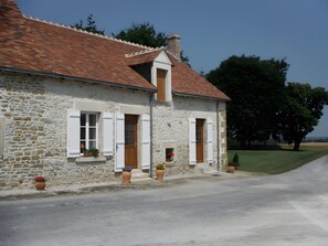 A stone house with a red-tiled roof, white shutters, and a small porch area with potted plants. - Guest Room 'Le Domaine Du Grand Vrillon' with Wi-Fi (Levroux)