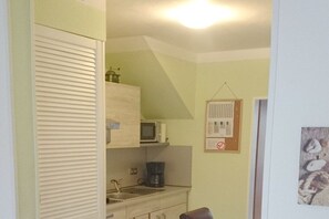 A compact kitchen with a microwave, coffee maker, and a small sink. - Holiday apartment with 1 bedroom (Norden)