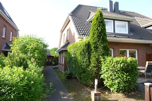 Ein Wohngebiet mit einem Haus, das ein geneigtes Dach, einen Schornstein und eine kleine angebaute Garage hat.