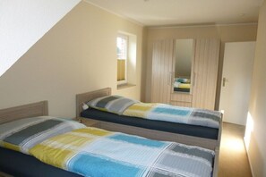 Ein Schlafzimmer mit zwei Betten, einem Fenster und einem Kleiderschrank.