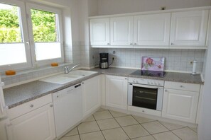 Eine Küche mit weißen Schränken, einem Spülbecken, einer Kaffeemaschine und einem Backofen.