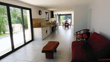 Un amplio espacio de sala con un sofá, un banco y una mesa de comedor con sillas.