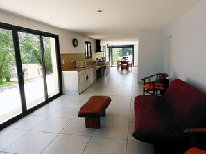 Un amplio espacio de sala con un sofá, un banco y una mesa de comedor con sillas.