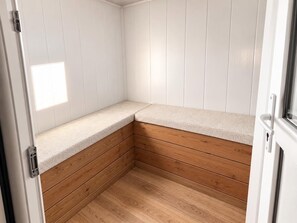 Ein Eckzimmer mit Holzboden, weißen Wänden und einer Bank.