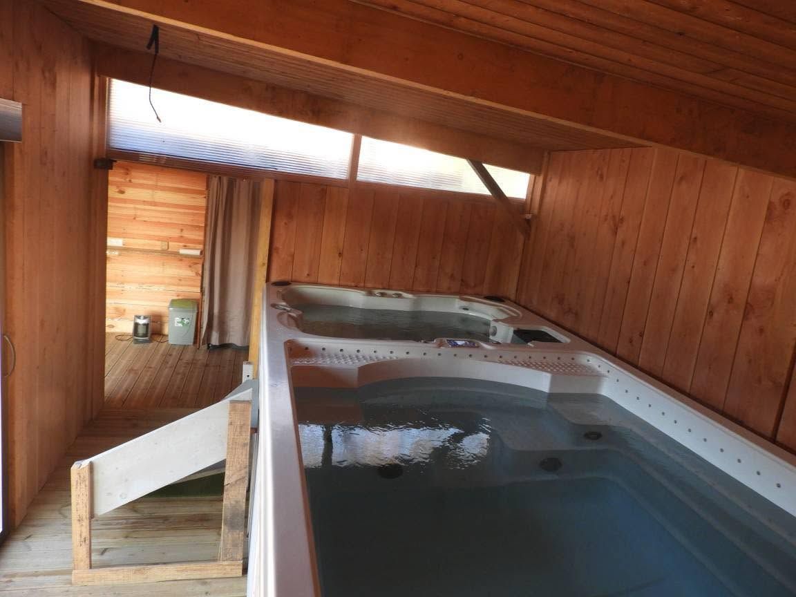 A wooden cabin with a hot tub and a small kitchenette.