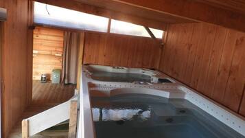 A wooden cabin with a hot tub and a small kitchenette.