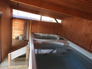 Una cabaña de madera con un jacuzzi y una kitchenette pequeña.