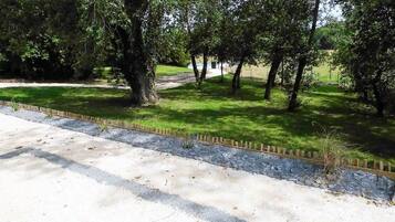 Un sendero pavimentado que conduce a una zona verde con árboles y una vista distante de un cuerpo de agua.