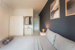 Ein Schlafzimmer mit einem Bett, einem Nachttisch mit Lampe, einer Kommode und einem Spiegel.