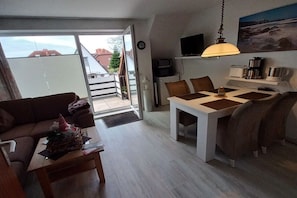 Een knus leefruimte met een eethoek, een bank, een koffieapparaat en een televisie.