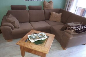 A brown sofa with cushions and a small wooden table with a tray. - Seahorses on the beach (Norddeich)