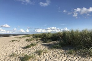 Een zandstrand met duinen en een heldere lucht.