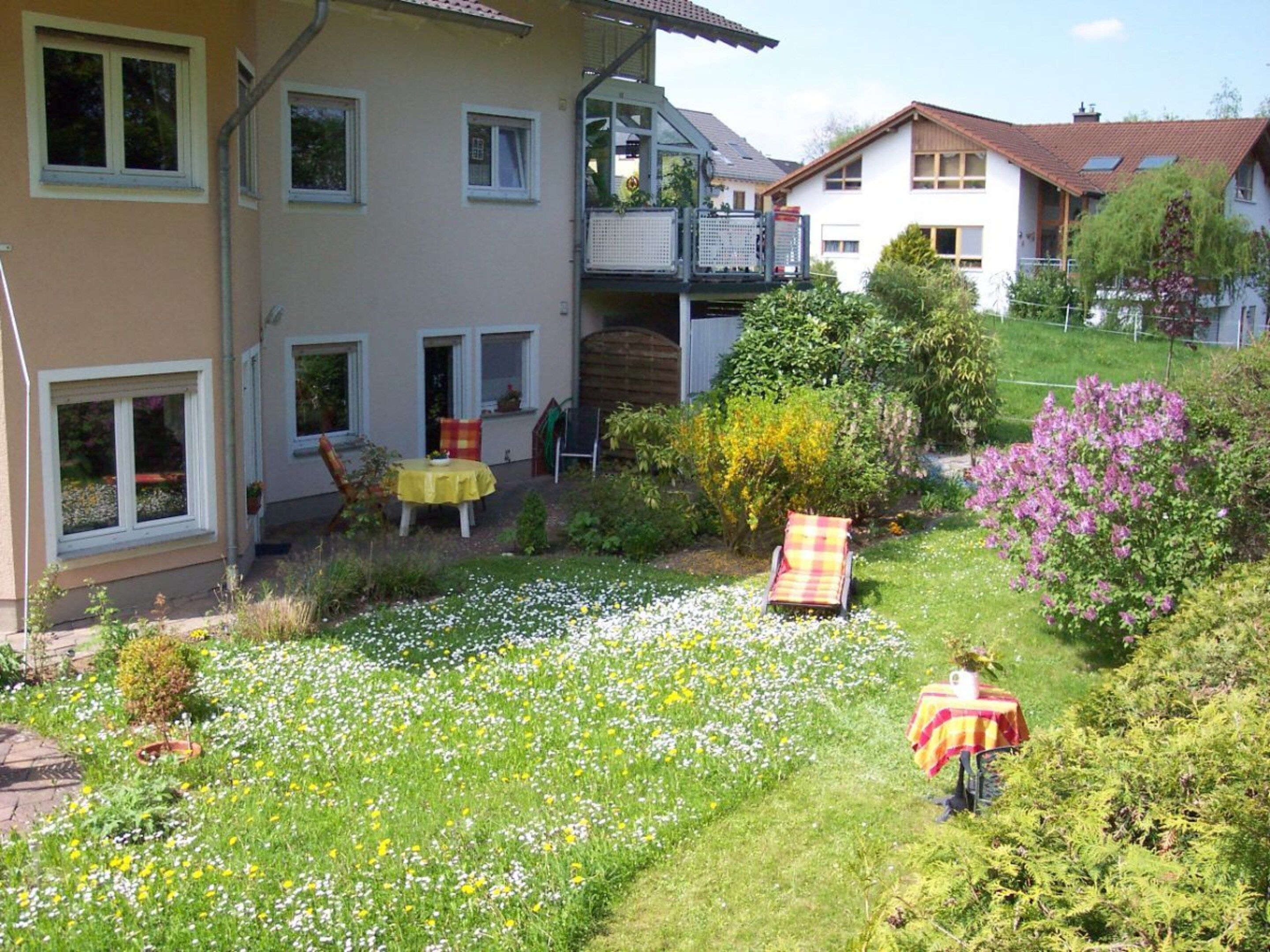A residential property with a garden, outdoor seating, and a visible balcony.