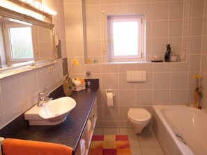 Ein Badezimmer mit Waschbecken, Toilette, Badewanne und einem Fenster.