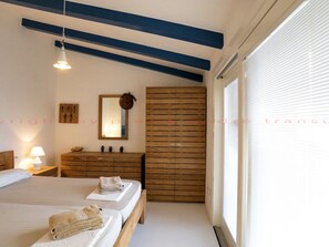 A bedroom with two beds, a dresser, a mirror, and a window with blinds. - 3-bedroom Villa (Trinità d'Agultu e Vignola)