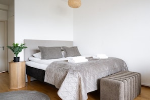 A neatly made bed with pillows, a bedside plant, and a small wooden stool. - Top Floor Park View Home By Lapland Host (Rovaniemi)