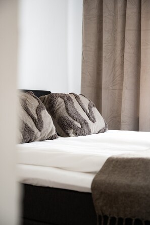 Ein Bett mit einer weißen Matratze und zwei Kissen mit einem strukturierten Muster.