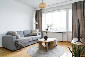 Ein modernes Wohnzimmer mit einem grauen Sofa, einem runden Holztisch und einem Fernsehschrank.