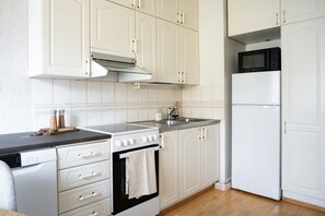 Een keuken met witte kastjes, een fornuis, een magnetron en een vaatwasser.
