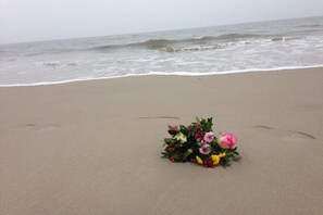 Ein Strand mit einem Blumenstrauß im Sand.
