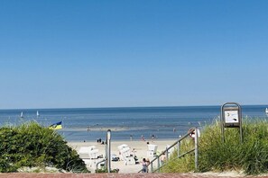 A beach with a clear sky, a flag, and a signboard. - Holiday apartment with 2 bedrooms (Wangerooge)