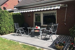 A patio with a table and chairs, a satellite dish, and a potted plant. - Holiday apartment with 1 bedroom (Norddeich)