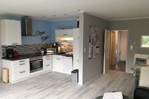 A modern kitchen with white cabinets, a black countertop, and a tiled backsplash. - Holiday apartment with 1 bedroom (Norddeich)