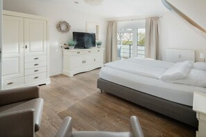 A bedroom with a large bed, a TV, a wardrobe, and a view through a window. - Apartment in Juist with swimming pool (Juist)