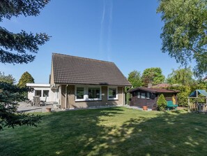A two-story house with a tiled roof, a front porch, and a small adjacent wooden structure. - Holiday Home in Renesse With Swimming Pool (Renesse)