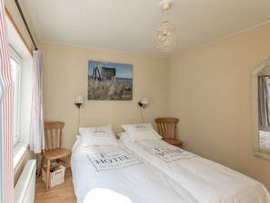 A bedroom with a bed, two nightstands, a lamp, a picture on the wall, and a window with curtains. - Holiday Home in Renesse With Swimming Pool (Renesse)