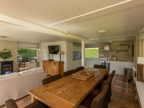 A modern kitchen with a dining area, a television, and a fireplace. - Holiday Home in Renesse With Swimming Pool (Renesse)