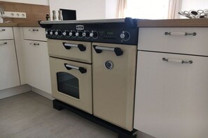 A kitchen with a vintage-style stove, a sink, and white cabinetry. - Holiday home in Vollerwiek with sauna (Vollerwiek)