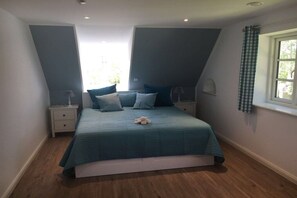 A bedroom with a bed, two bedside tables, a window with curtains, and a view of the outdoors. - Holiday home in Vollerwiek with sauna (Vollerwiek)
