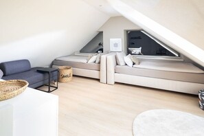 A loft bedroom with a bed, a sofa, a small table, and a window. - Holiday apartment in Juist with swimming pool (Juist)