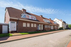 A row of brick houses with a paved driveway and a clear sky. - Holiday apartment in Juist with swimming pool (Juist)