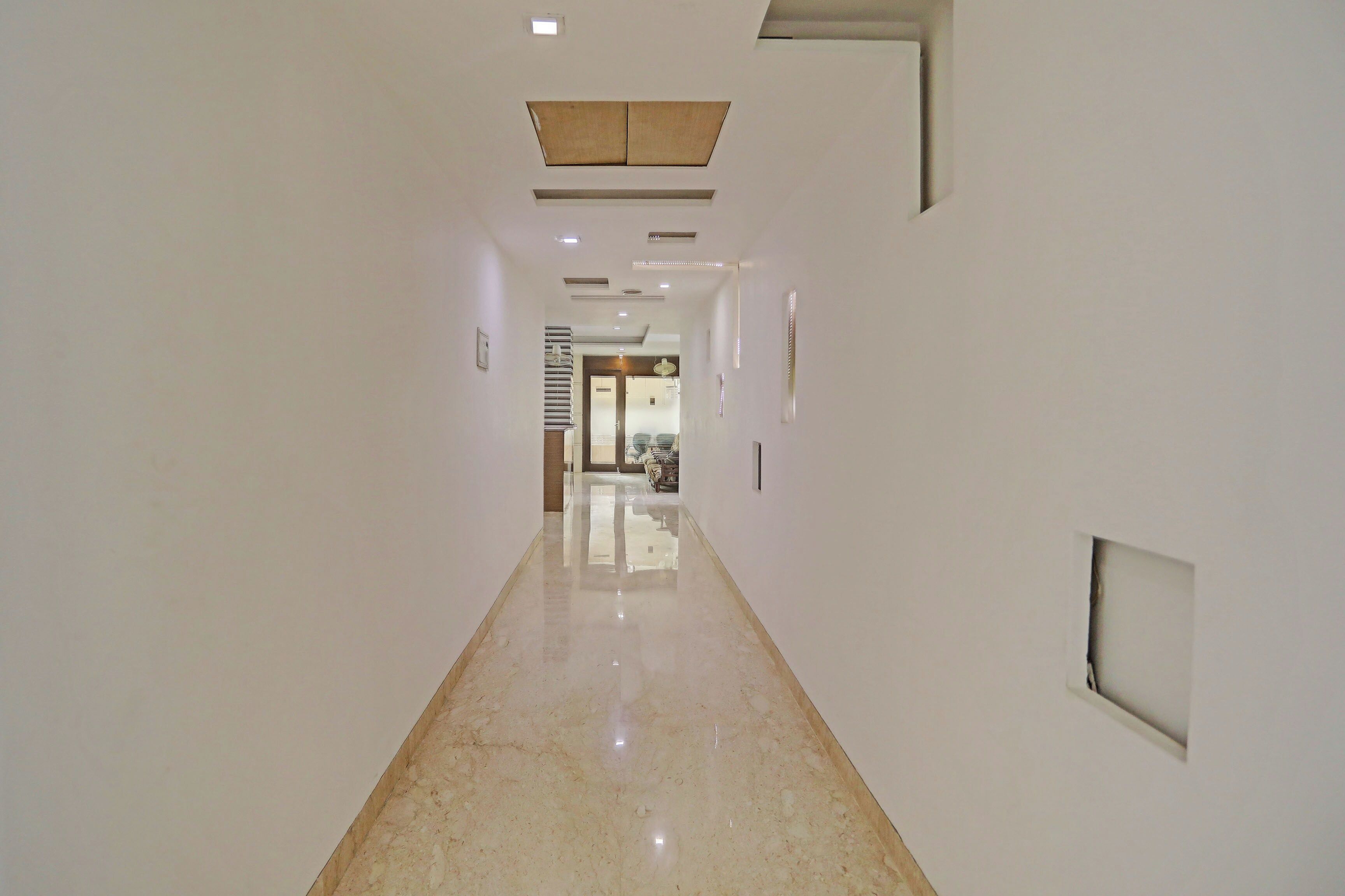 A corridor with a polished floor, recessed lighting, and a door at the end.