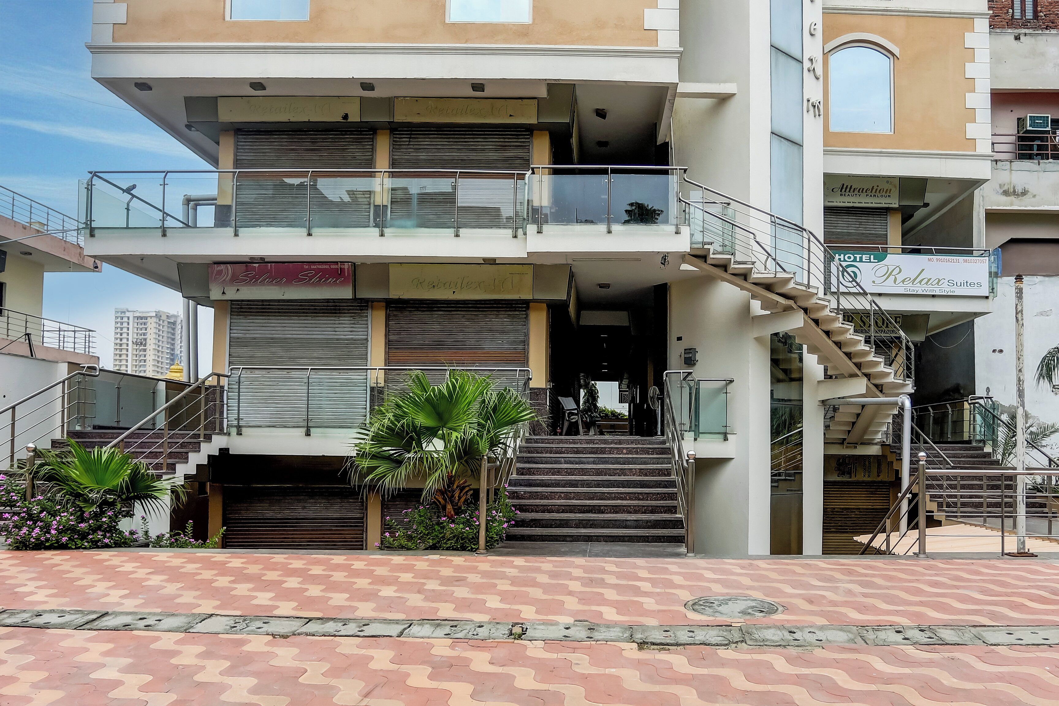Un hotel de varios pisos con una escalera que lleva a la entrada, un balcón y un letrero que dice 'Relax Suites'.