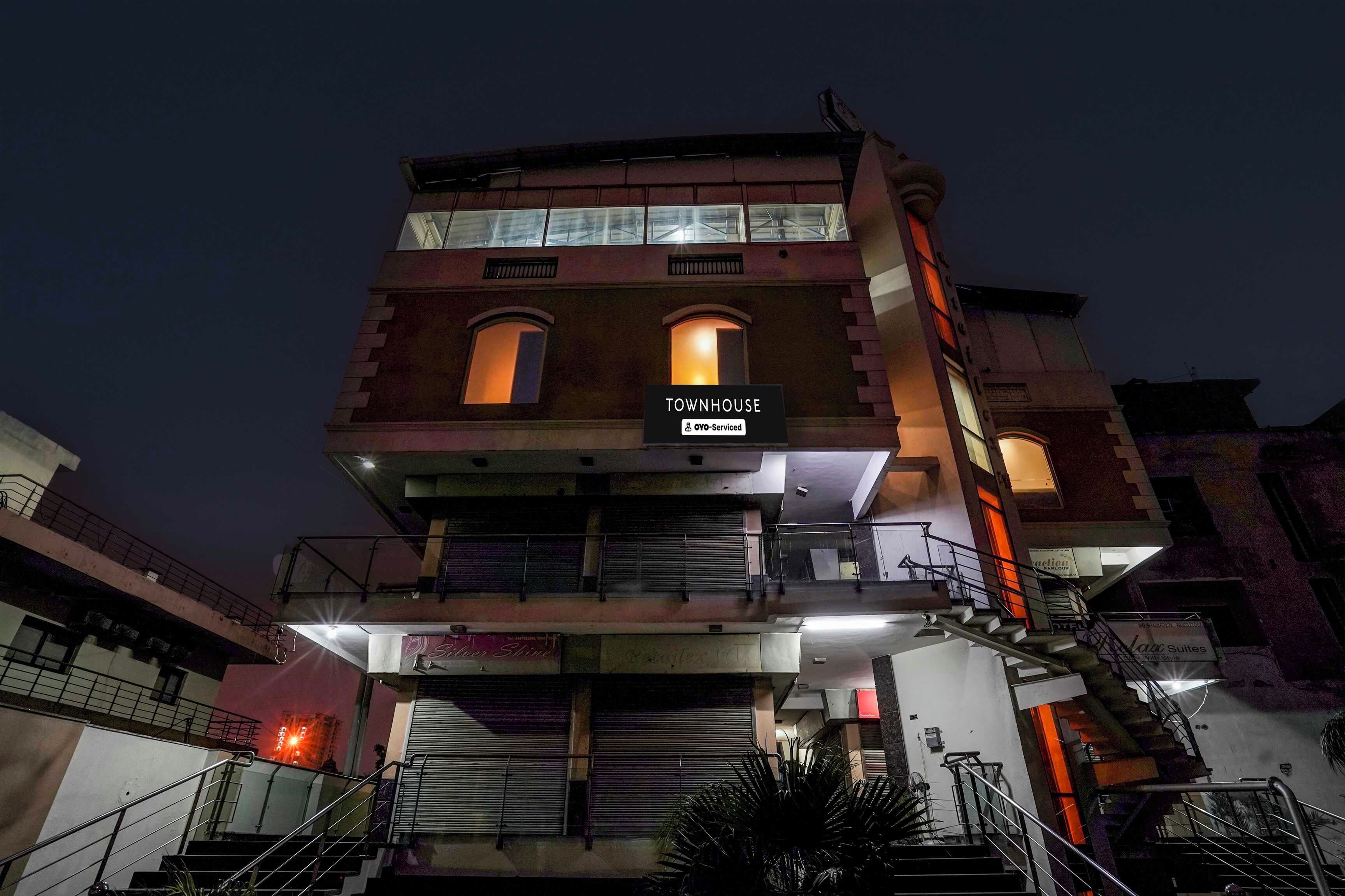 Un edificio de varios pisos con un letrero que indica 'TOWNHOUSE' y servicios 'YO-Serviced'.