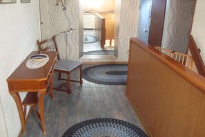 A dining area with a wooden table and chairs, a mirror, and patterned rugs on the floor. - Holiday apartment with 2 bedrooms (Dornumersiel)