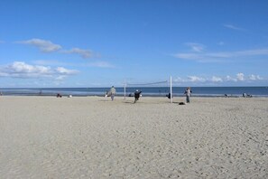 Ein Beachvolleyballfeld mit Spielern und Zuschauern.