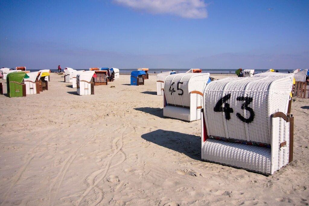 Les cabanes de plage numérotées 43 et 45, avec une plage de sable et l’océan en arrière-plan.