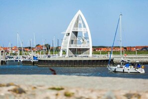 A coastal marina with a distinctive white sailboat-shaped building, multiple boats docked, and a clear sky. - Holiday apartment in Juist with swimming pool (Juist)