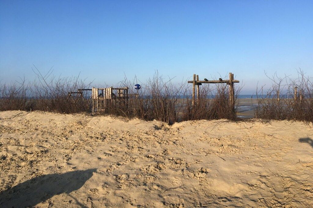 Una playa arenosa con una estructura de madera y un cartel.