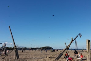 Ein Strand mit Holzgebäuden, Menschen und Drachen.