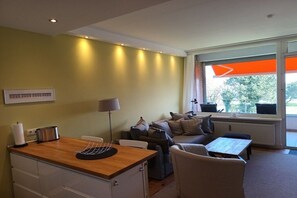 Ein Wohnzimmer mit einer Couch, einem Tisch und einer Küchenzeile inklusive Toaster.