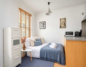 Ein gemütliches Schlafzimmer mit Bett, Nachttisch und einer kleinen Küchenzeile.