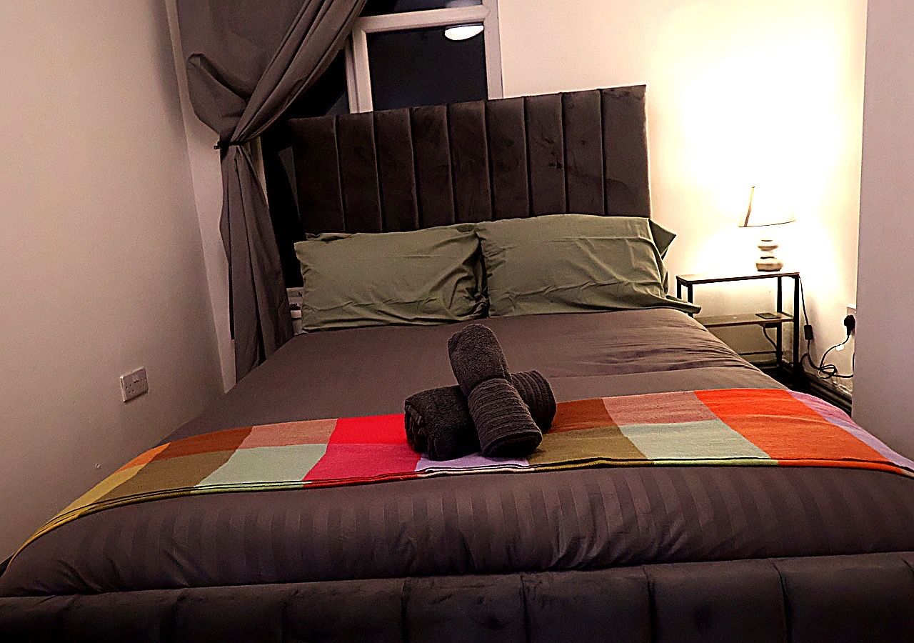 A bed with a quilt, pillows, and rolled towels.
