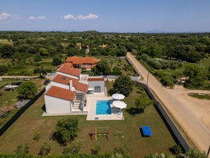 Ein Wohnhaus mit Pool, Sitzgelegenheiten im Freien und Tennisplatz.