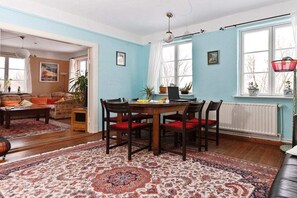 Ein Zimmer mit Esstisch, Stühlen, einer Couch und einem gemusterten Teppich.